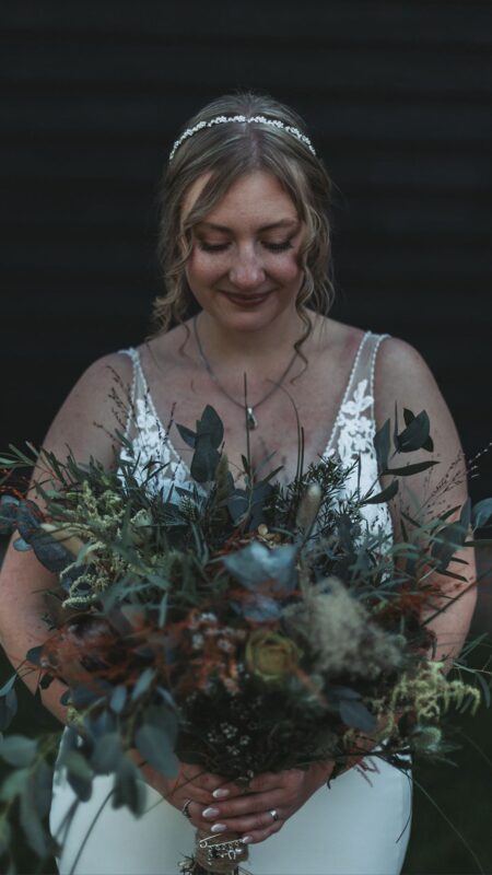 Bride holds bouquet of white flowers and grasses