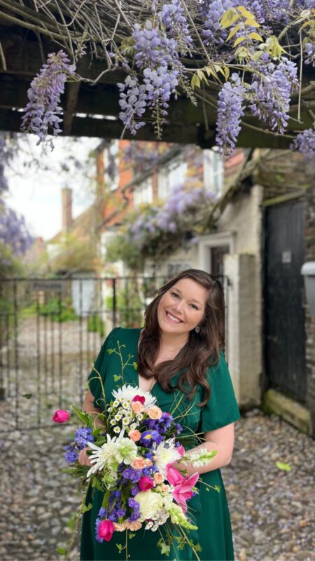 Loose bouquet held by a woman under a wisteria tree. The bouquet is a combination of tulips, carnations, rose and daisies.