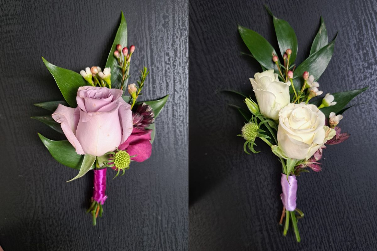 Two buttonholes. Both use ruscus and waxflower. The groom's has a purple rose and the groomsman have two white roses that are smaller (spray roses)