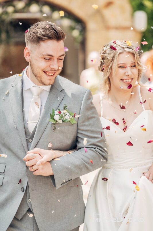 Beth and Alex walk under their dried confetti