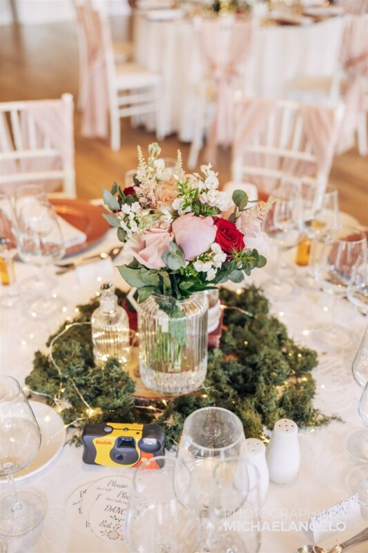A centrepiece with moss, books, perfume bottle, case and flowers