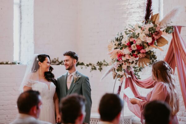 Bride and Groom look lovingly at each other by their wedding arch.